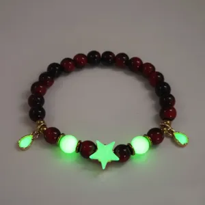 Close-up of luminous beaded bracelet featuring green glowing star and drop charms