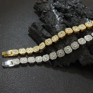 Nahaufnahme von goldenen und silbernen 11mm achteckigen Iced-Out-Halsketten auf dunklem Fels.