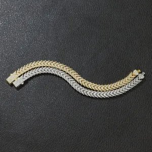 Detailansicht von gold- und silberfarbenen Iced-Out-Fischgräten-Tennisarmbändern auf Leder.