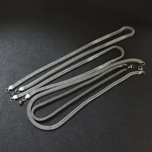 Macro detail view of multiple stainless steel Franco chain necklaces on black leather