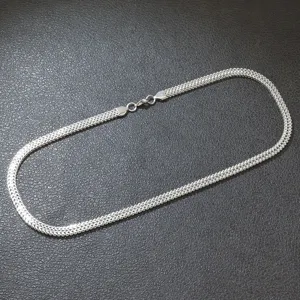 Detail shot of silver stainless steel double row Franco chain necklace on leather