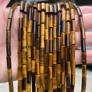 Macro detail of 4x13mm natural yellow tiger eye cylindrical beads for jewelry making.