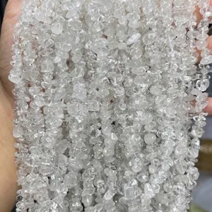 Close-up detail of natural clear quartz crystal chips with pre-drilled holes for DIY jewelry.