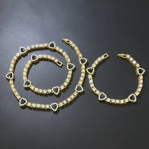 Detaillierte Makroansicht der vergoldeten Tenniskette mit schwarzen Herzanhängern und Steinen.
