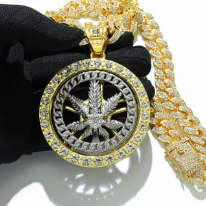 Close-up detail of iced out rotating maple leaf pendant with thick gold cuban link chain