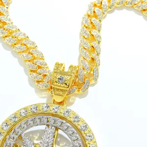 Close-up detail of hip-hop iced-out rotating maple leaf pendant and gold Cuban chain