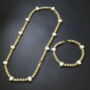 Detailansicht eines goldenen Tennis-Schmucksets mit weißen Emaille-Herzen und Strasssteinen.