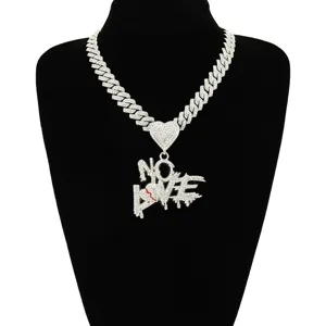 Close-up of iced out NO LOVE pendant necklace featuring a broken heart on a Cuban chain