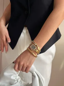 Detail einer goldenen Uhr mit Kristalllünette und bunten Steinarmbändern am Handgelenk