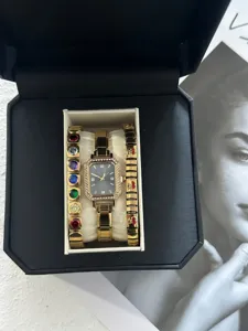 Elegantes Set aus goldener Quarzuhr und Kirscharmband in einer schwarzen Box.