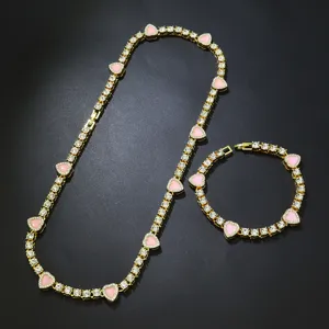Nahaufnahme von vergoldetem Tennis-Halsketten- und Armbandset mit rosa Herzen.