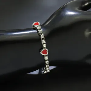 Nahaufnahme eines silbernen Tennisarmbands mit funkelnden Strasssteinen und roten Herzen.