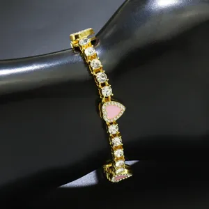 Detailaufnahme eines goldfarbenen Tennisarmbands mit rosa Herzanhängern und funkelnden Steinen