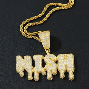 Makro-Detail des goldenen NISH-Buchstabenanhängers mit klaren Zirkonia-Steinen