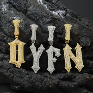 Detailansicht der Hip-Hop-Zirkonia-Buchstabenanhänger in Gold und Silber auf Fels.