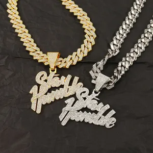 Detail view of iced out Stay Humble pendant with cuban link chain in gold and silver