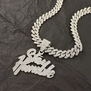Close-up of iced-out Stay Humble pendant necklace on a textured black background.