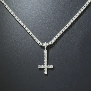 Detailed macro view of an iced out inverted cross pendant on a silver tennis chain.