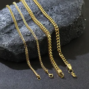 Macro detail of four gold plated stainless steel Franco chains displayed on a dark rock