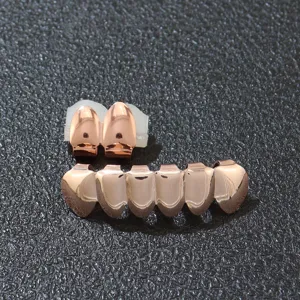 Nahaufnahme-Detail von glänzenden rosagoldenen Hip-Hop-Zahn-Grillz auf schwarzem Grund