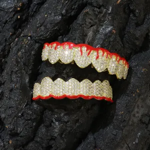 Detailed view of gold-tone grillz with red dripping enamel and micro-paved zircons.