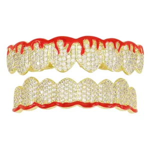 Close-up of gold-plated copper grillz with red enamel drip and clear cubic zirconia
