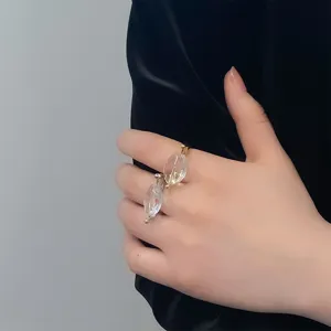 Detailopname van elegante goud- en zilveren ringen met heldere glaselementen aan hand.