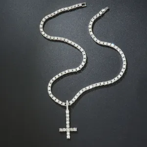Detailed view of silver iced out inverted cross pendant on a sparkling tennis chain