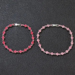 Macro view of two elegant tennis bracelets featuring red and pink flower-shaped crystals.