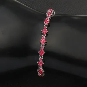 Detailed view of red crystal flower-shaped links on a silver tennis bracelet