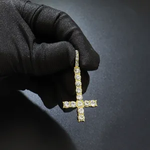 Close-up of iced out inverted cross pendant with sparkling clear stones in gold finish