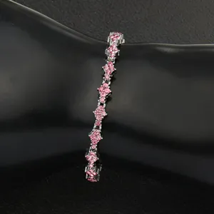 Close-up detail of a silver tennis bracelet with pink floral cross crystal accents