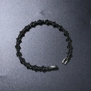 Nahaufnahme eines schwarzen Blumen-Tennisarmbands mit funkelnden Steinen auf dunklem Grund.