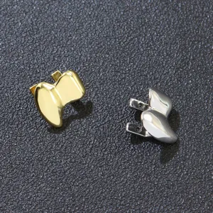 Detalle de fundas dentales de colmillos de vampiro dorados y plateados brillantes.