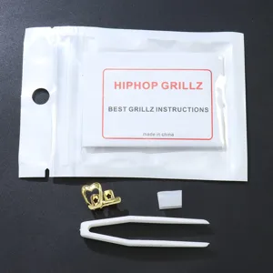 Detailansicht eines goldfarbenen Zahngrills mit Herzmuster, Pinzette und Silikon