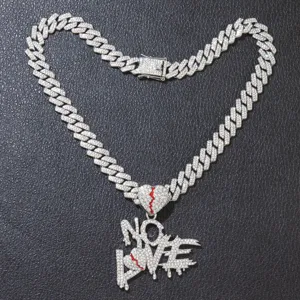 Detail view of iced out NO LOVE broken heart pendant on silver Cuban link chain
