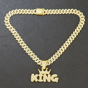 Macro detail of a gold iced out KING crown pendant with pavé Cuban link chain necklace.