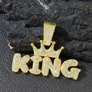 Detailed macro shot of iced out gold KING crown pendant with shimmering rhinestones.