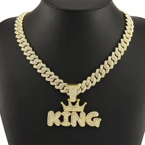Detailed macro view of the iced out KING crown pendant on a gold Cuban link chain necklace.
