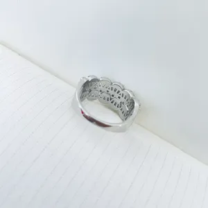 Detail view of a silver-toned micro-pave zircon ring with intricate hollow patterns.