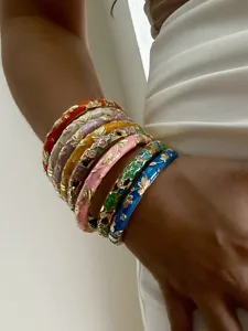 Detailed view of stacked colorful gilded floral enamel bangles in a retro ethnic style