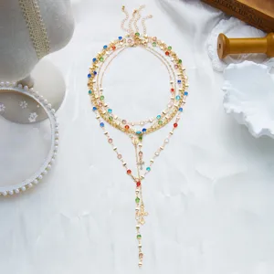 Détail du collier en Y à double couche avec des strass colorés et des pendentifs croix