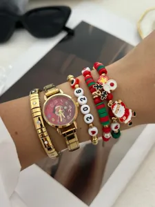 Primo piano del festoso orologio natalizio color oro e del set di braccialetti