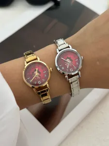 Primo piano di orologi natalizi festivi con quadranti rossi e cinturini in metallo su un polso
