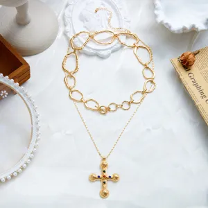 Vue détaillée d'un collier croix en or vintage avec des accents de pierres colorées.