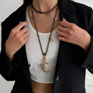 Detail view of a Bohemian gold moon and star pendant on an adjustable brown cord necklace