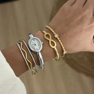 Detailansicht eines eleganten silbernen Uhren- und goldenen Infinity-Armband-Sets