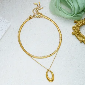 Close-up of minimalist layered gold necklace with geometric oval pendant and snake chain