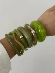 Detail van gelaagde groene harsarmbanden met bamboe ontwerp en parel accenten