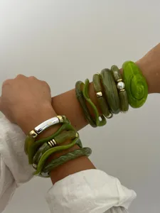 Detailweergave van gelaagde groene hars armbanden met gouden accenten en een parel